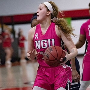 Female basketball player wearing pink jersey while playing.
